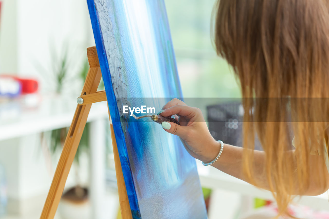 Woman painting on canvas at home