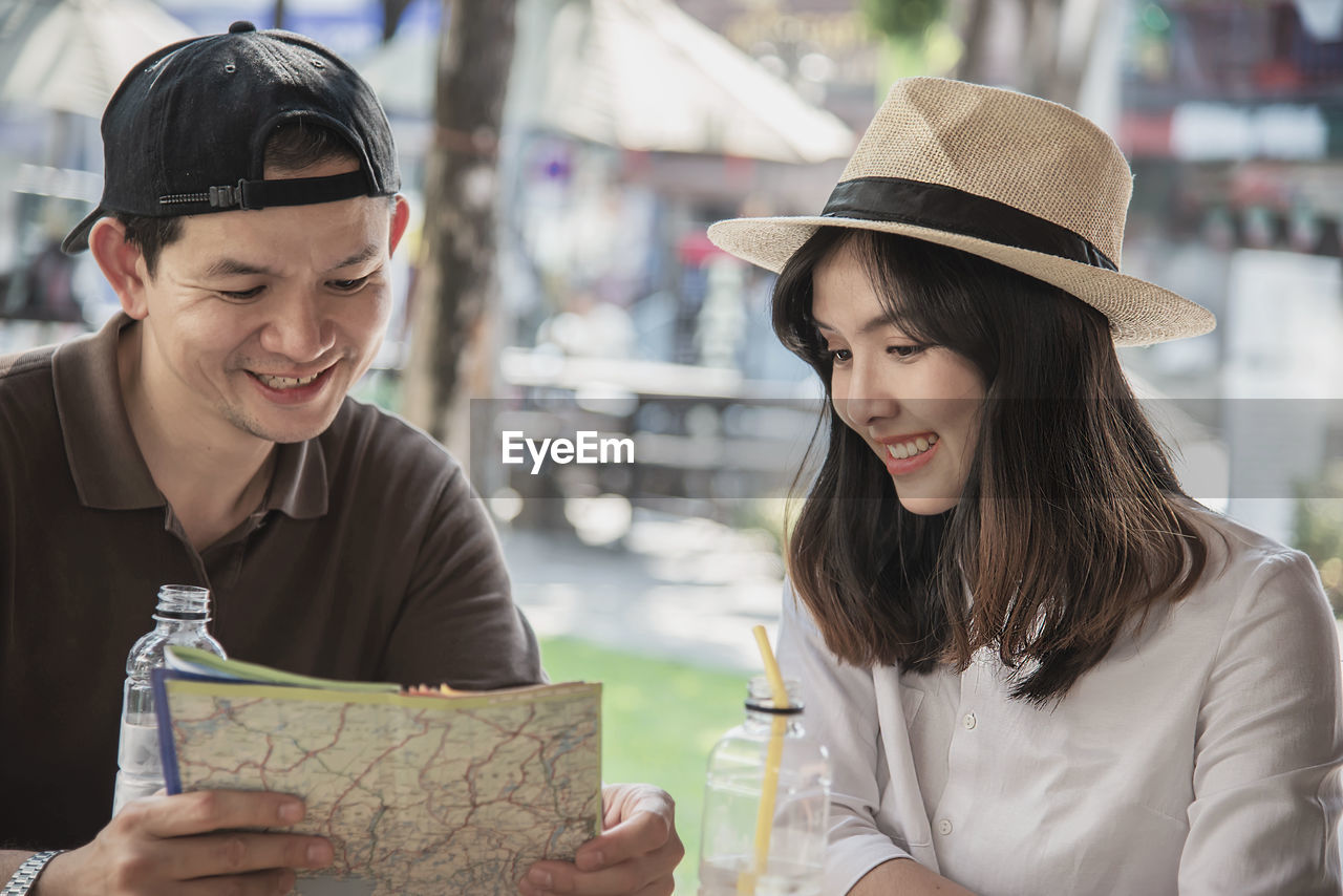 Smiling couple holding map sitting at restaurant