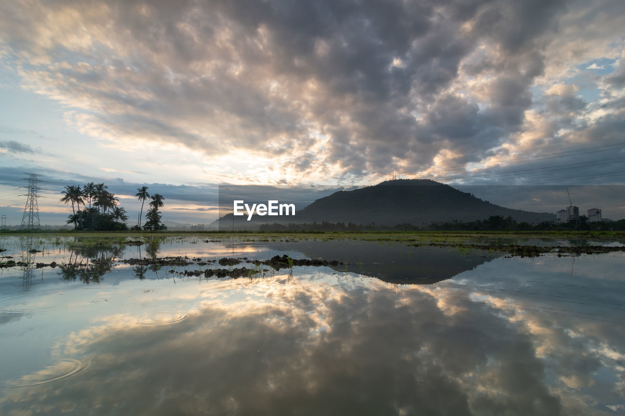 reflection, sky, water, cloud, morning, dawn, nature, beauty in nature, scenics - nature, sea, sunrise, mountain, environment, horizon, sunlight, shore, landscape, tranquility, land, body of water, tranquil scene, coast, tree, travel destinations, outdoors, travel, no people, sun, beach, dramatic sky, twilight, plant, ocean, wave, mountain range, idyllic