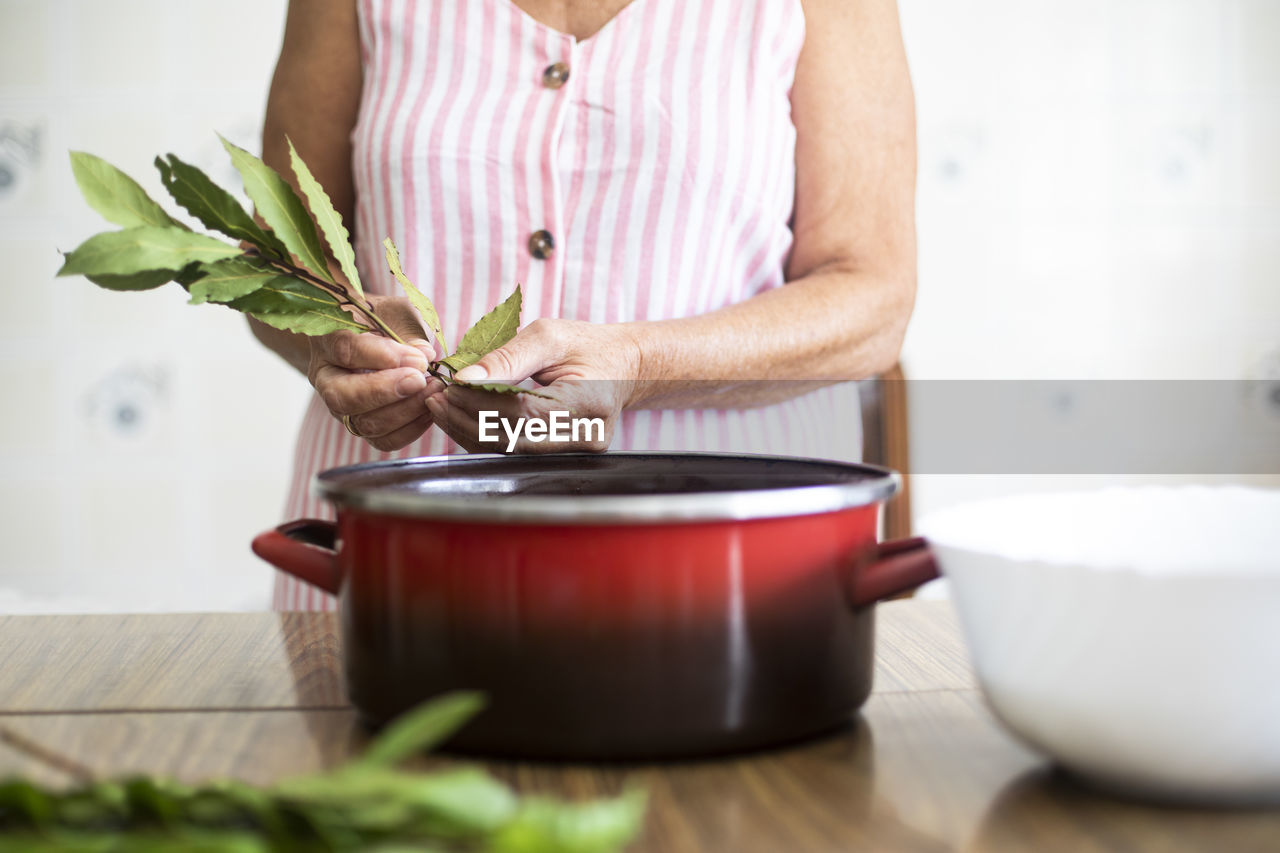 Woman using laurel for cooking in kitchen