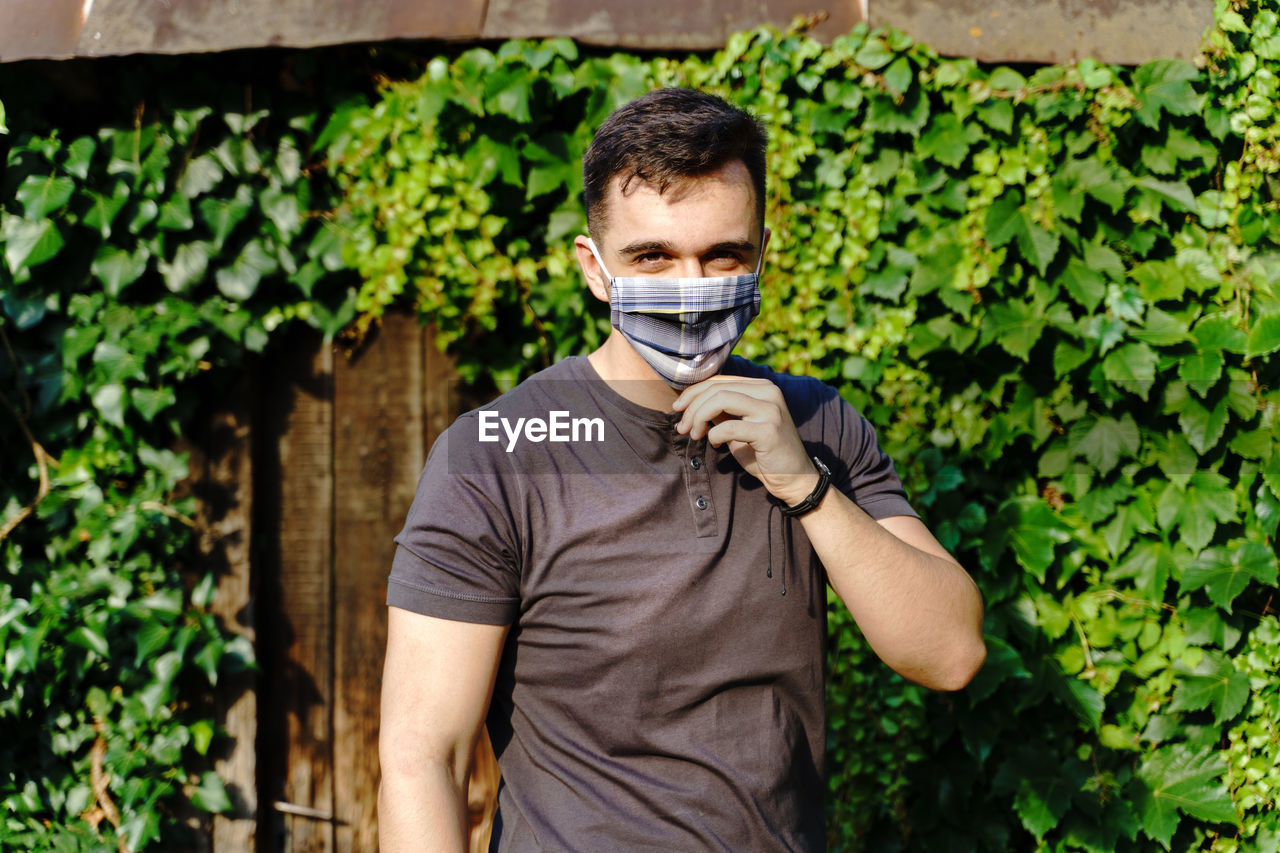 Portrait of young man standing against plants