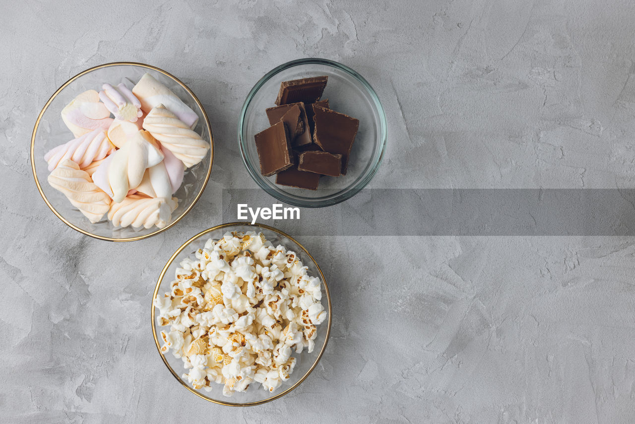 Popcorn, marshmallow, chocolate bar pieces in bowls. ingredients for cooking, copy space