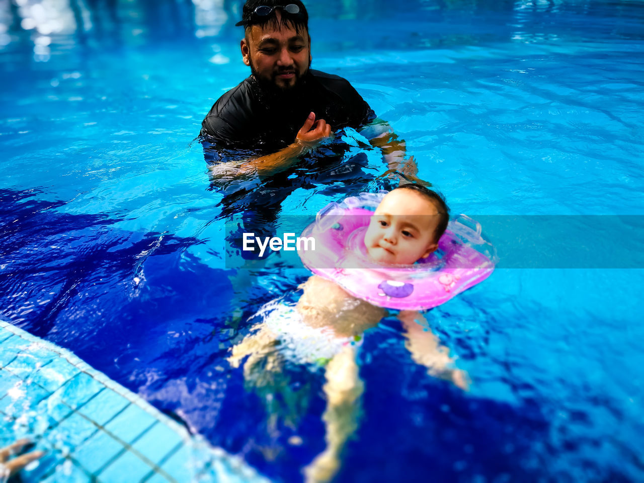 Father swimming with baby in pool