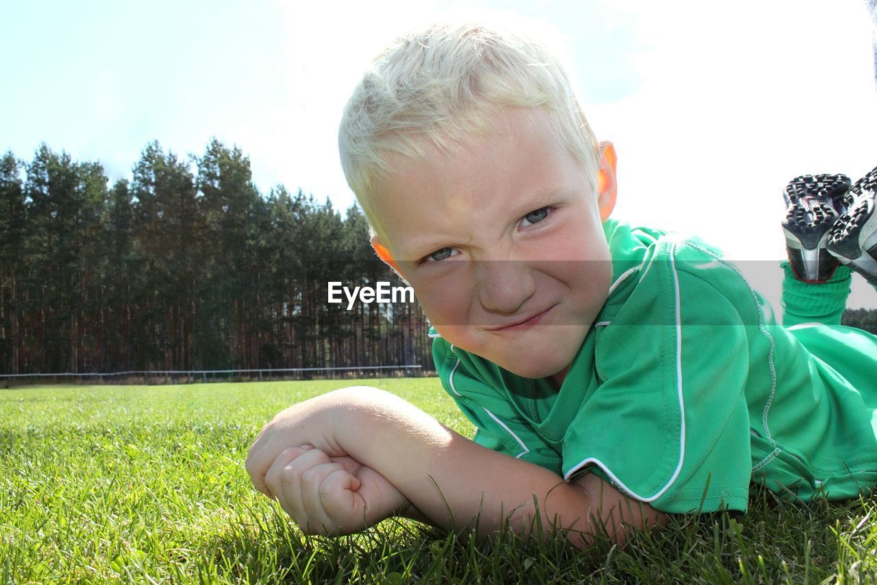 Portrait of boy lying down on field