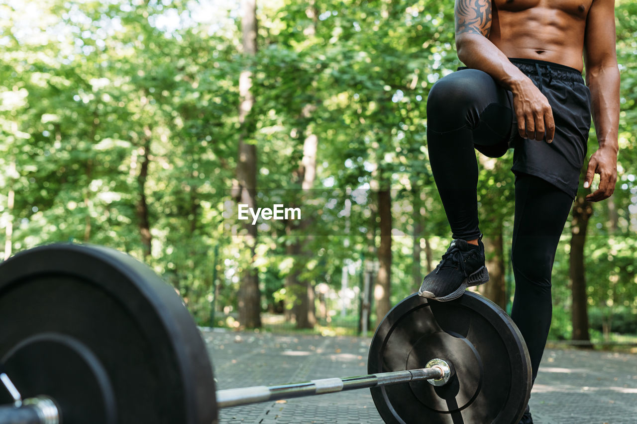 Low section of man standing by barbell on road