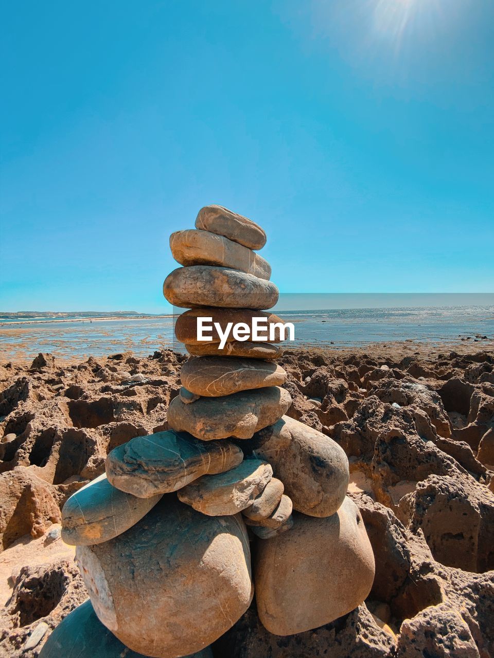 STACK OF STONES ON BEACH AGAINST SKY