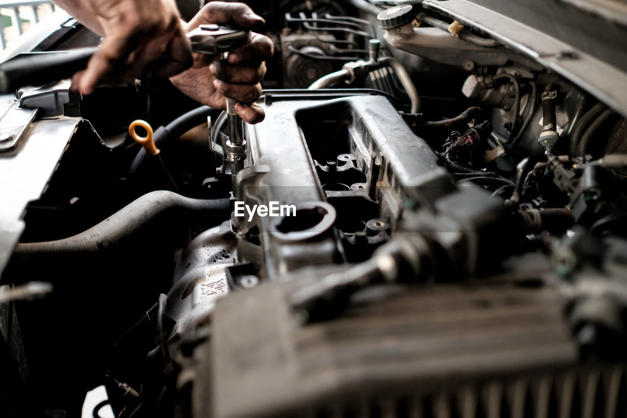 Cropped hand of mechanic repairing car at garage