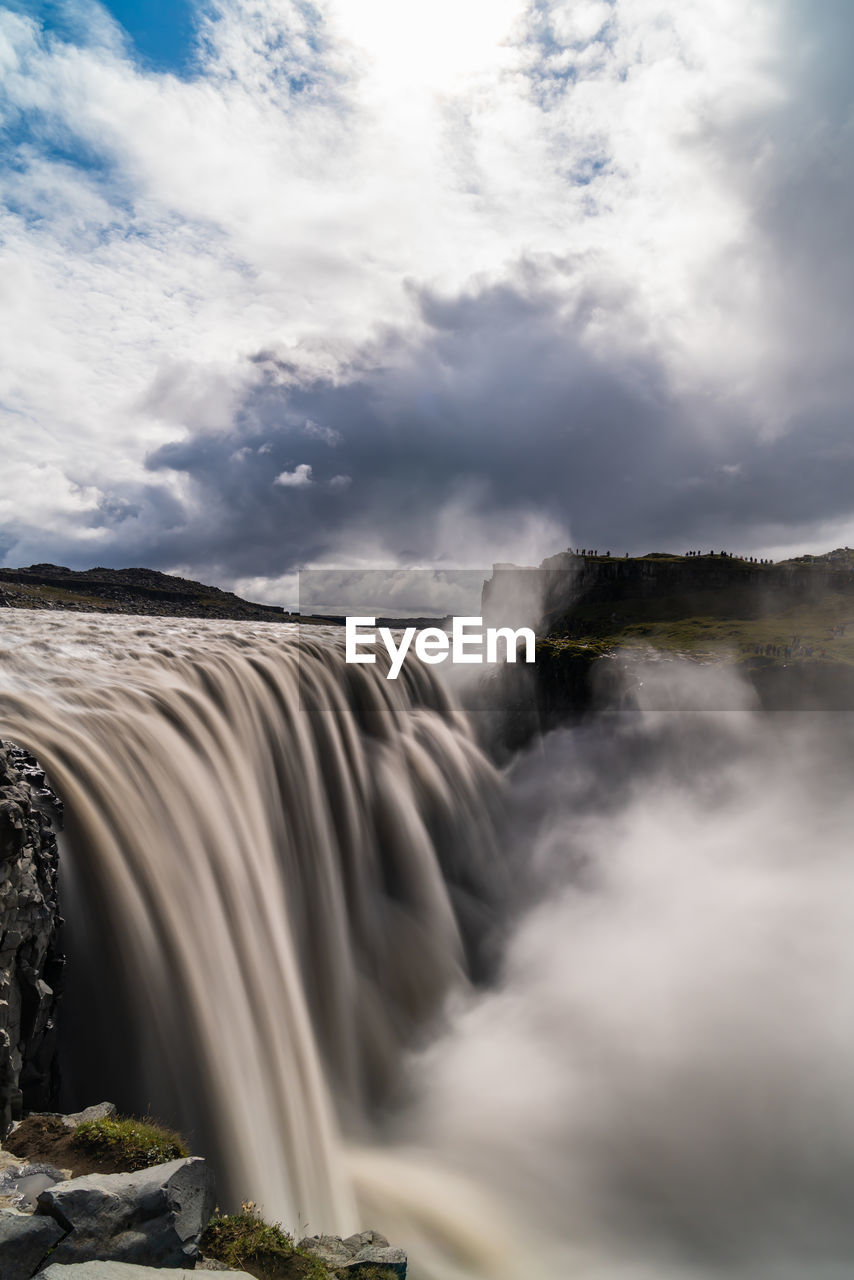 View of waterfall against cloudy sky - dettifoss