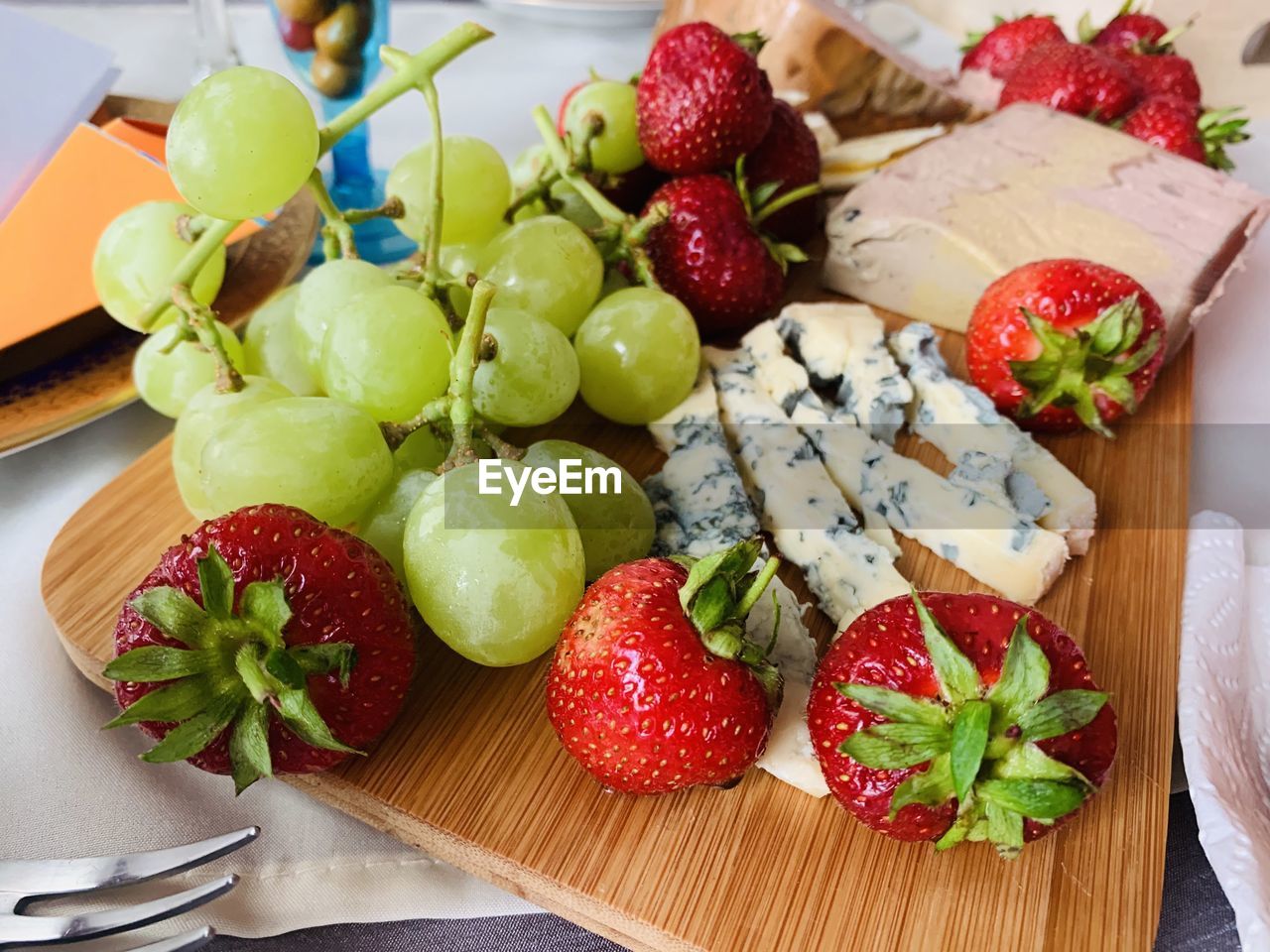 High angle view of strawberries, cheese and grapes on table
