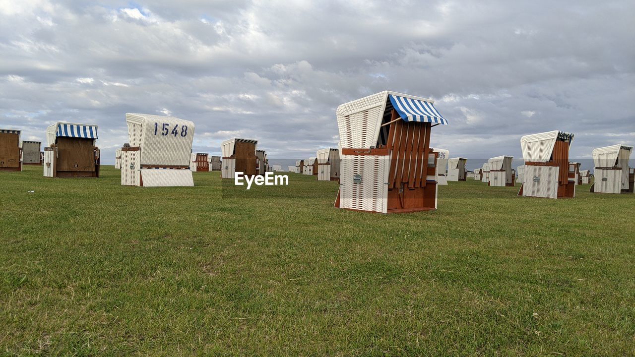 HOODED CHAIRS ON FIELD AGAINST SKY