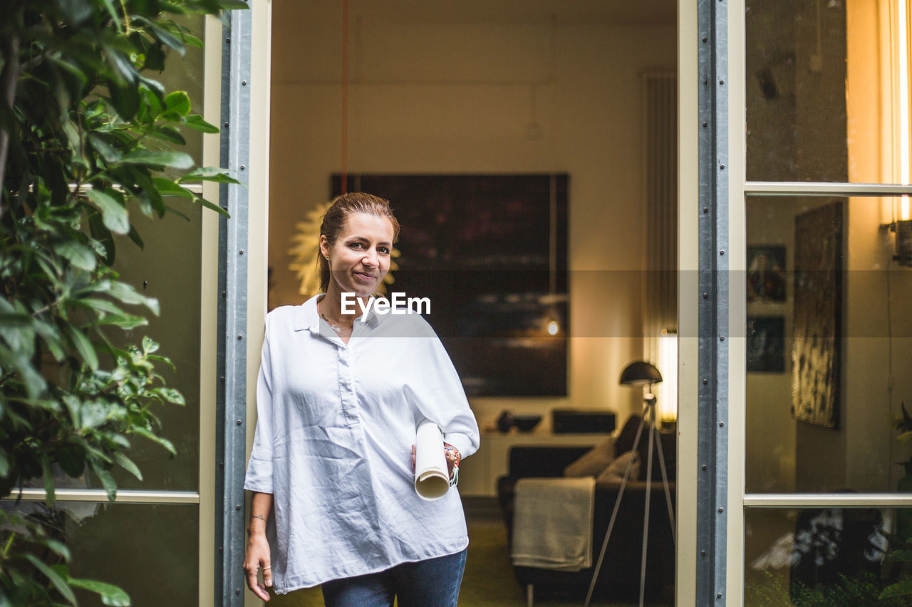 Portrait of female design professional standing at house entrance