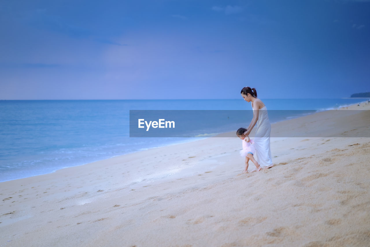 WOMAN ENJOYING AT BEACH AGAINST SKY