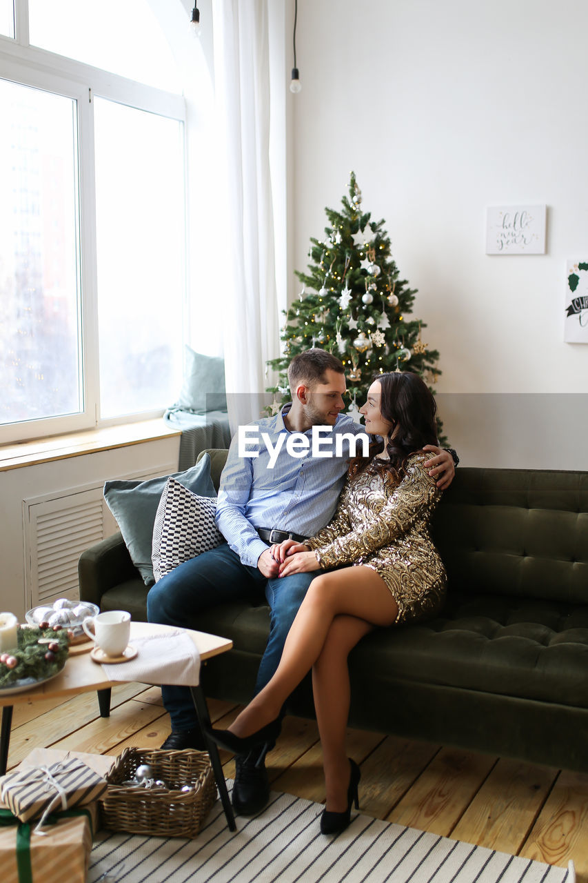 A young man and a woman in love are preparing together and celebrating new year and christmas home