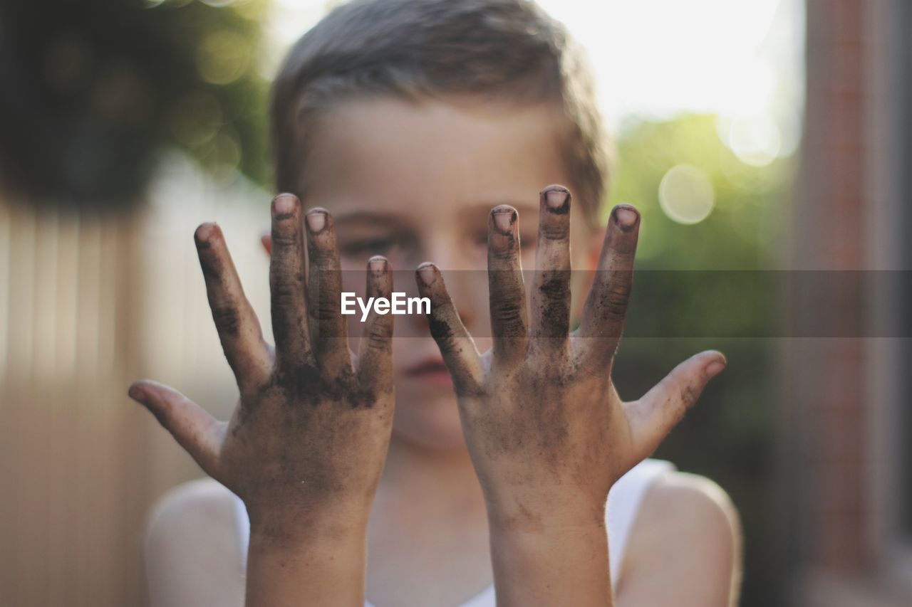 Close-up of boy looking at his dirty hands