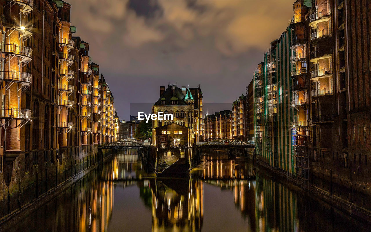 Canal amidst buildings in city at dusk