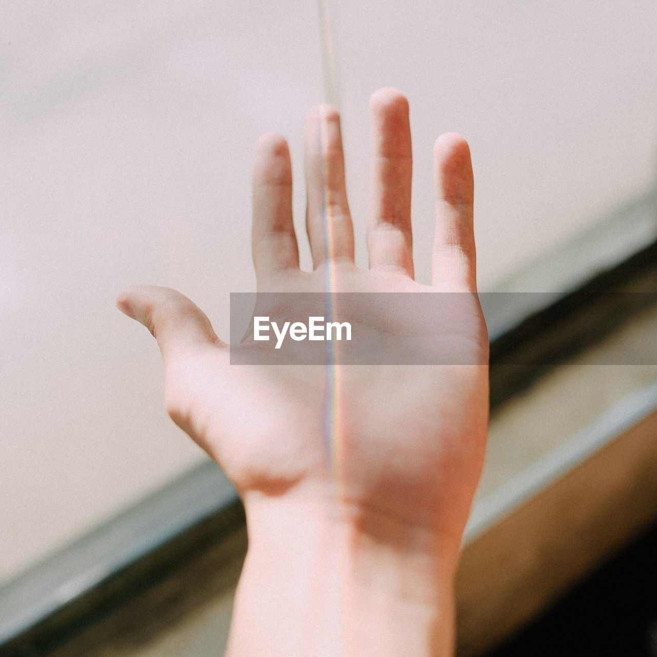 Cropped hand of woman with spectrum against wall