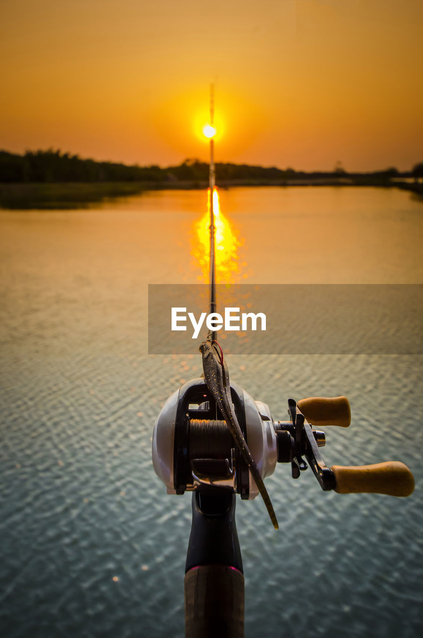 Fishing rod over sea against clear sky during sunset