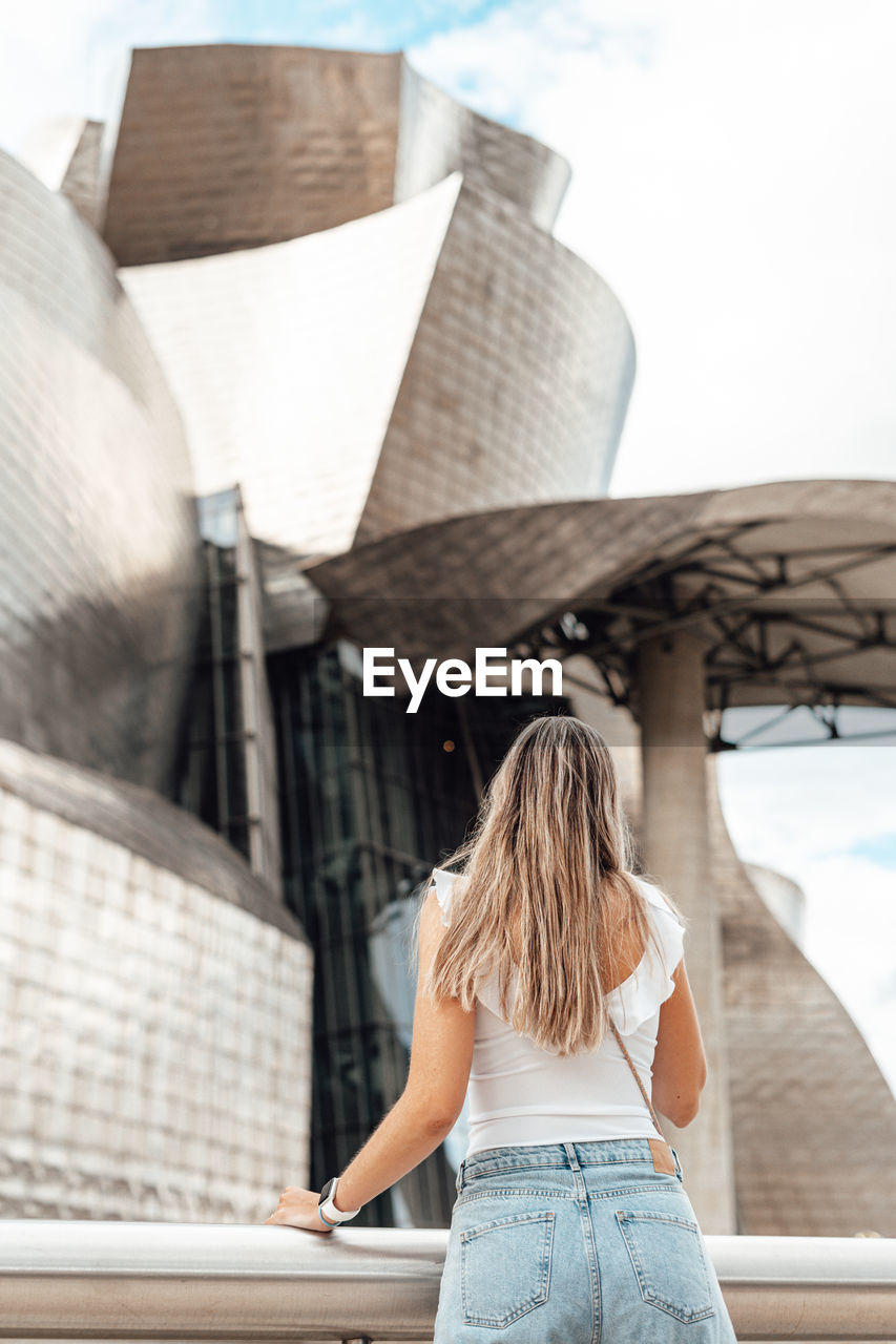 Rear view of woman standing against building