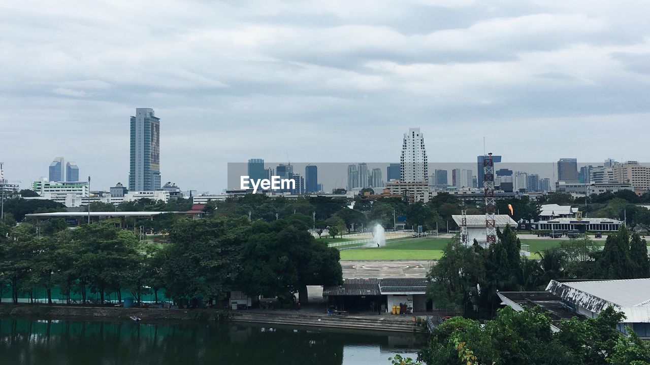 City at waterfront against cloudy sky