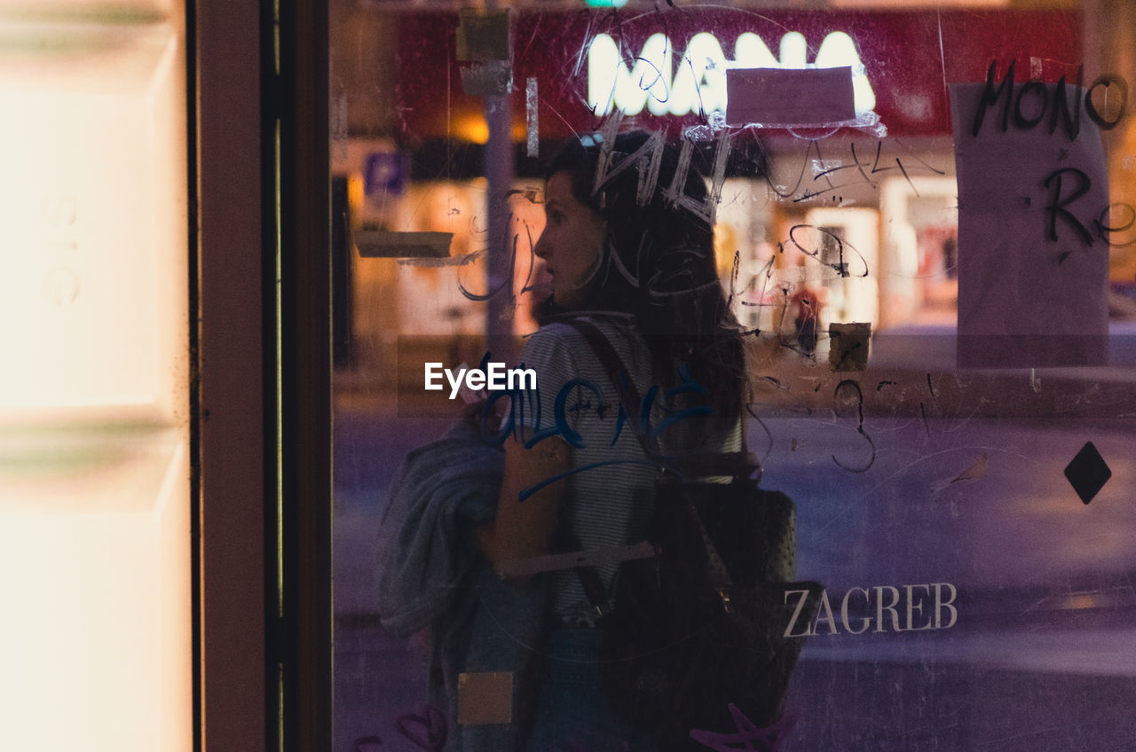 REAR VIEW OF PEOPLE STANDING BY WINDOW WITH TEXT
