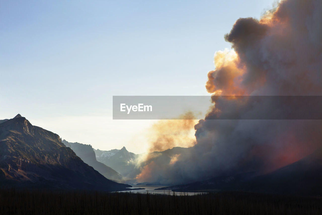 Smoke emitting from glacier national park during sunset against clear sky