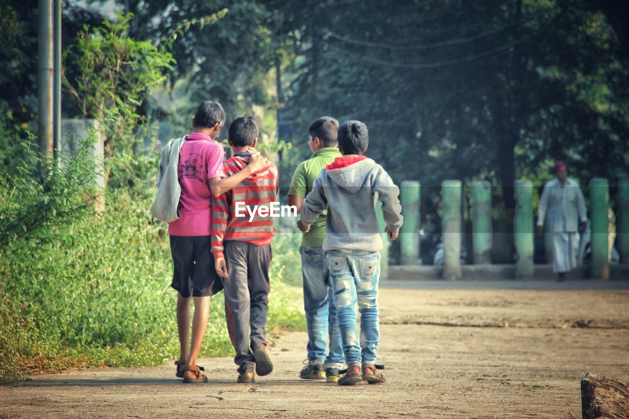 Rear view of boys walking on footpath