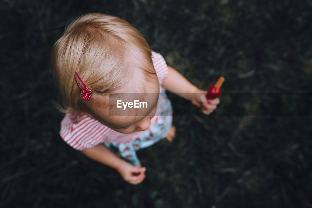 High angle view of baby girl holding flavored ice cream