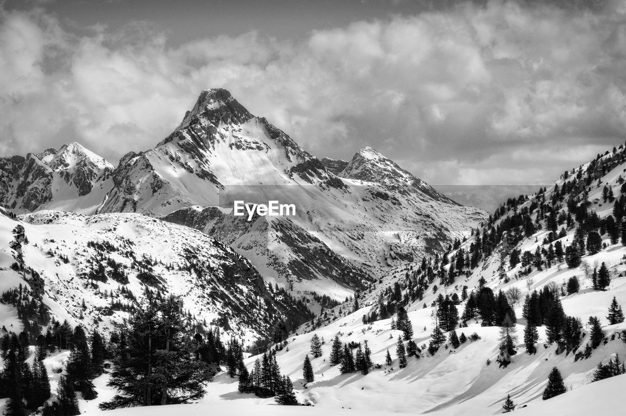 Snowcapped mountains against cloudy sky