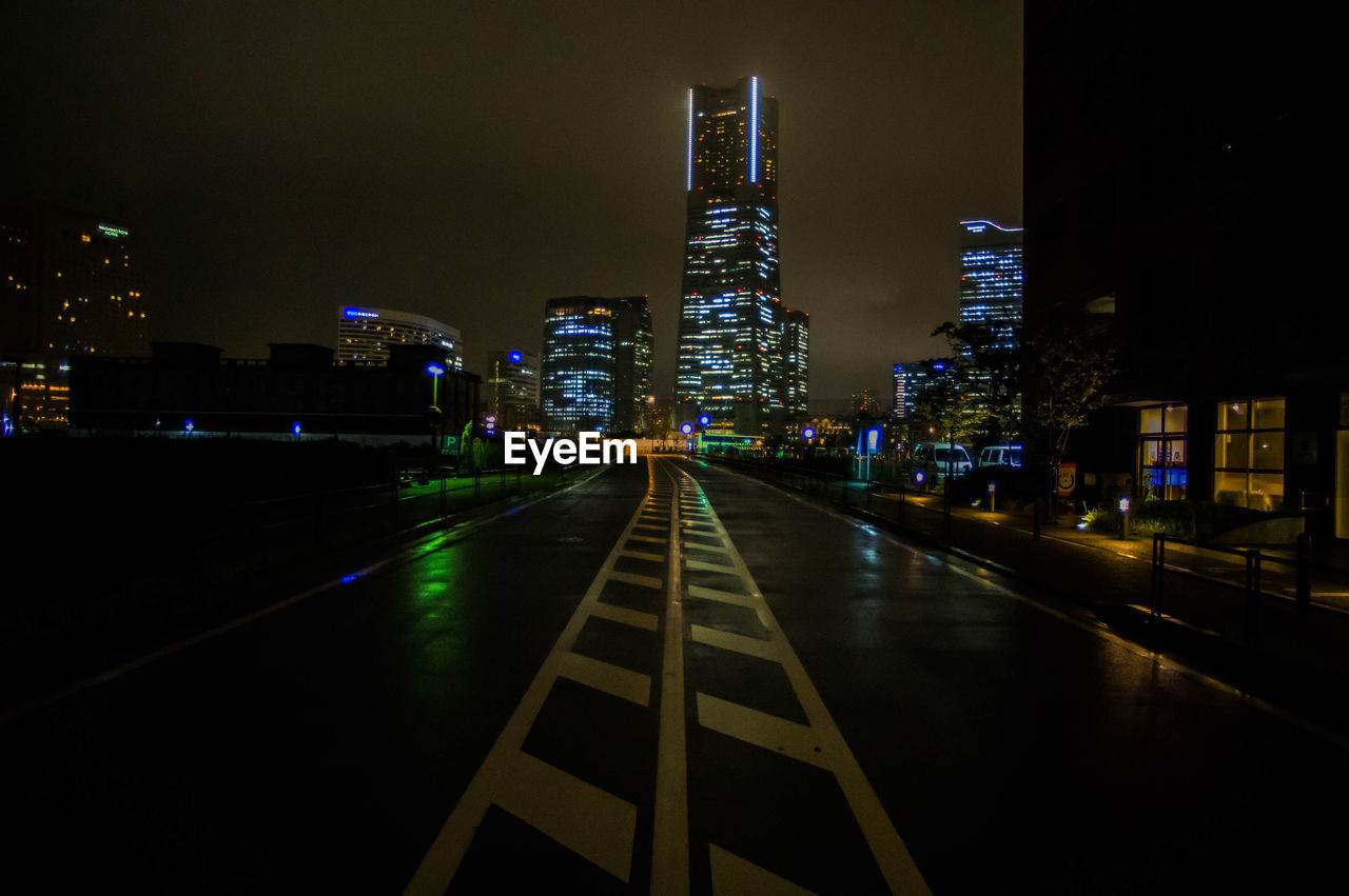 View of empty road by illuminated yokohama landmark tower at night