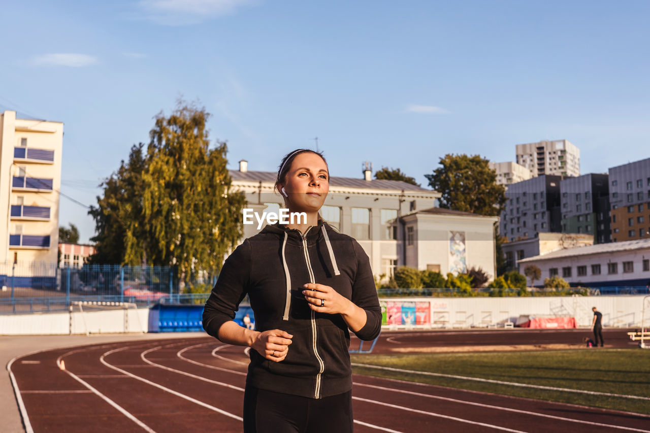 Woman running in stadium against sky