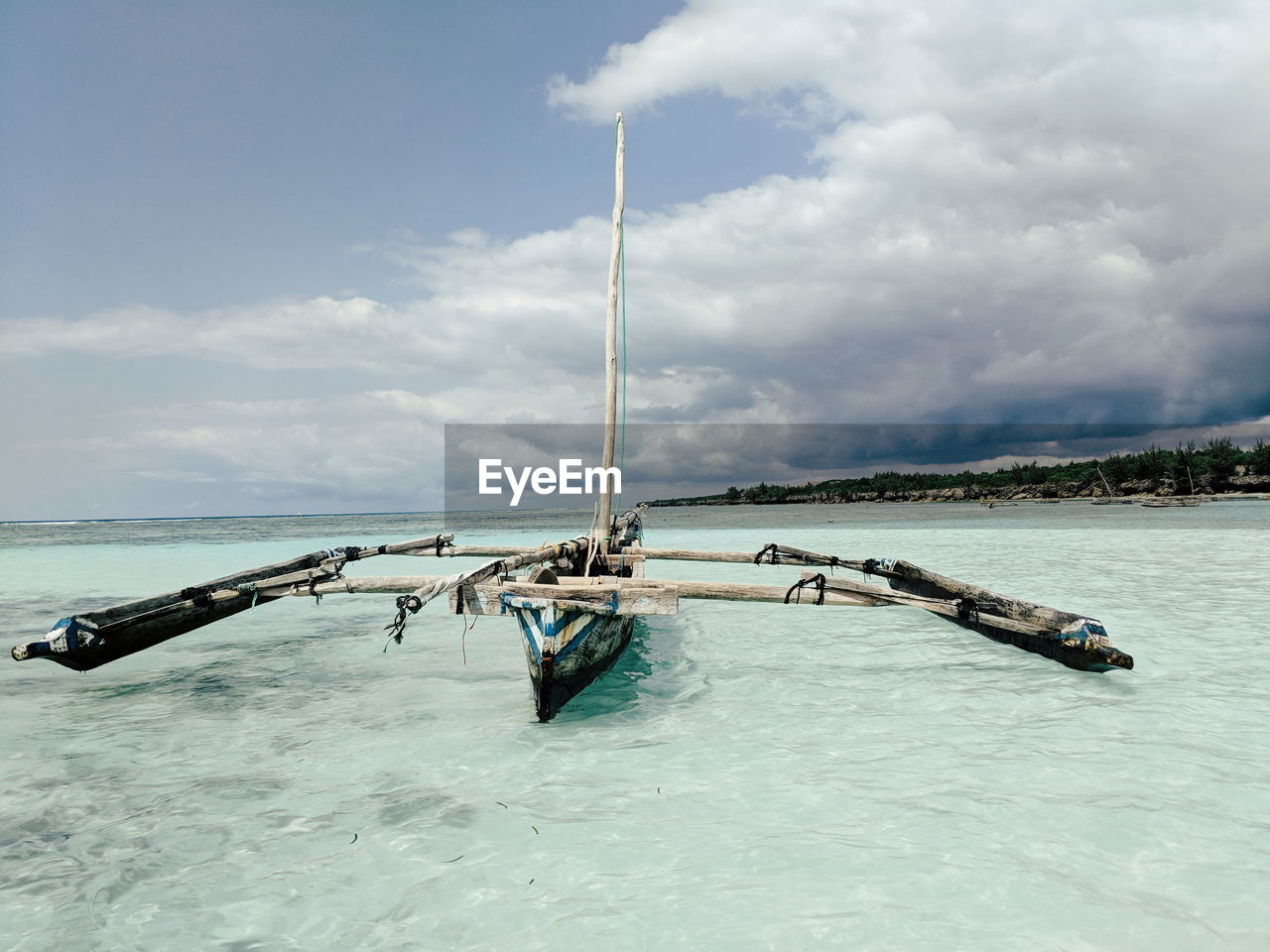 Fishing boat on beach by sea against sky