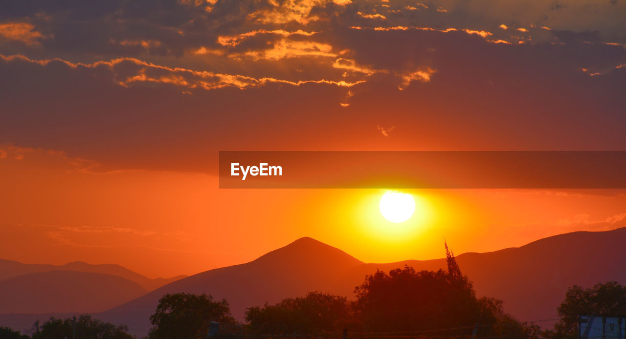 Scenic view of silhouette mountains against romantic sky at sunset