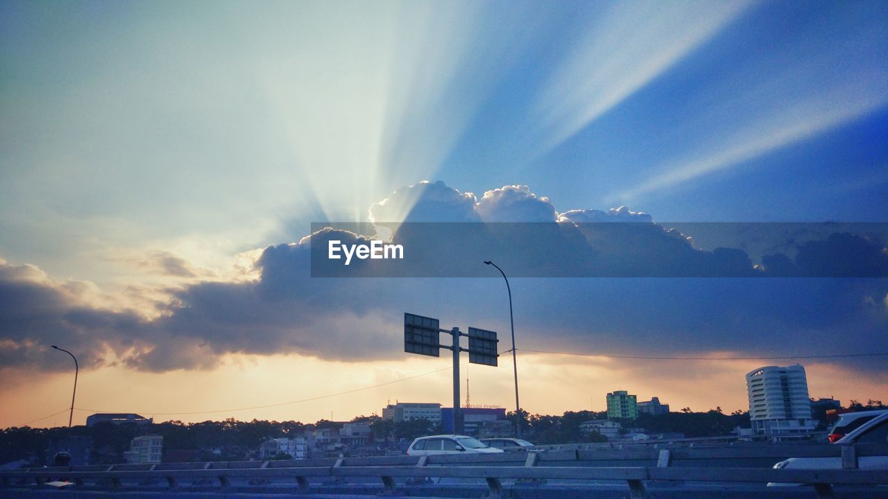 STREET BY BUILDINGS AGAINST SKY AT SUNSET