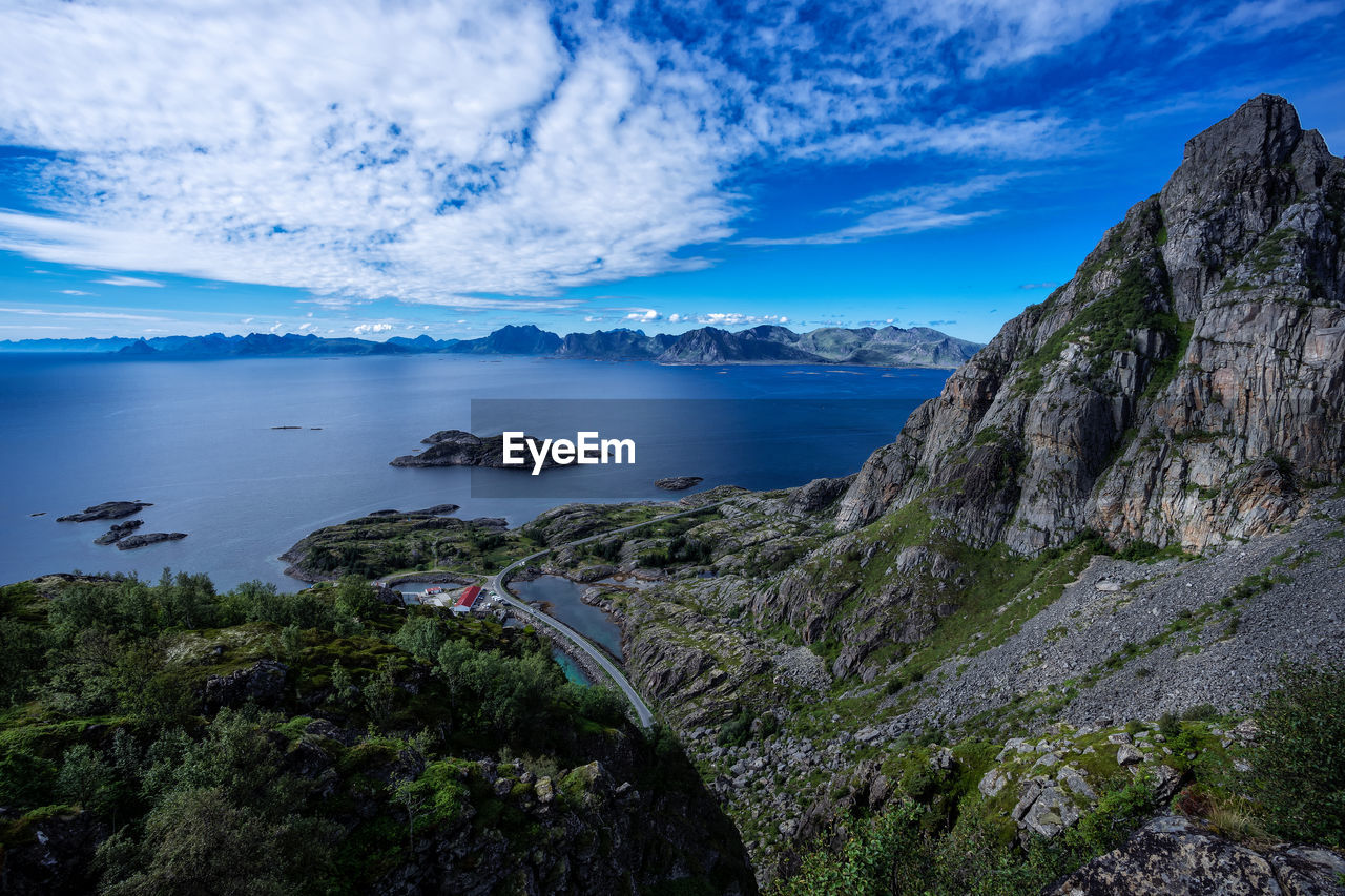 Panoramic view of road between fjord and mountains over the horizon