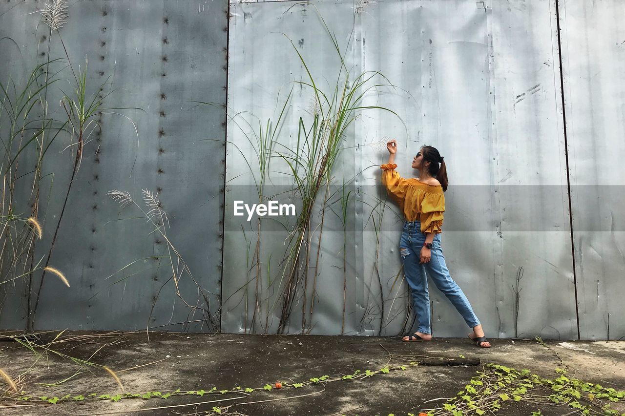 Full length of woman standing against wall