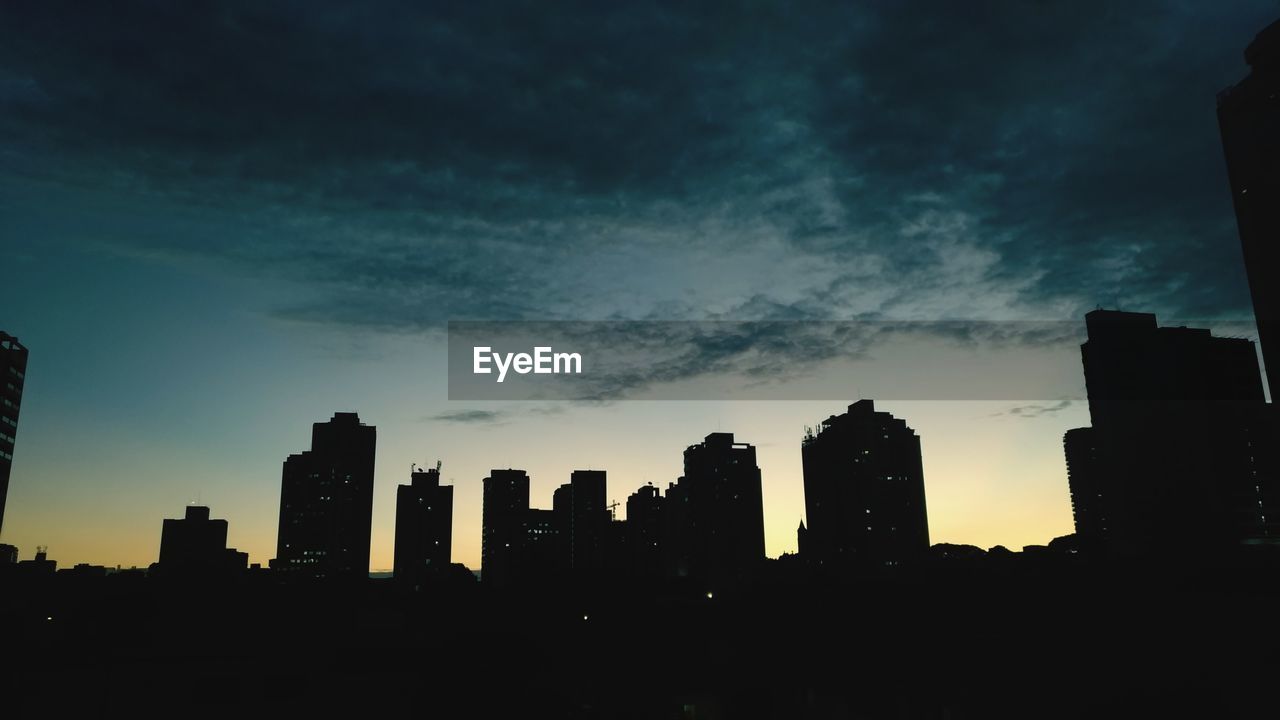 SILHOUETTE BUILDINGS IN CITY AGAINST SKY AT SUNSET