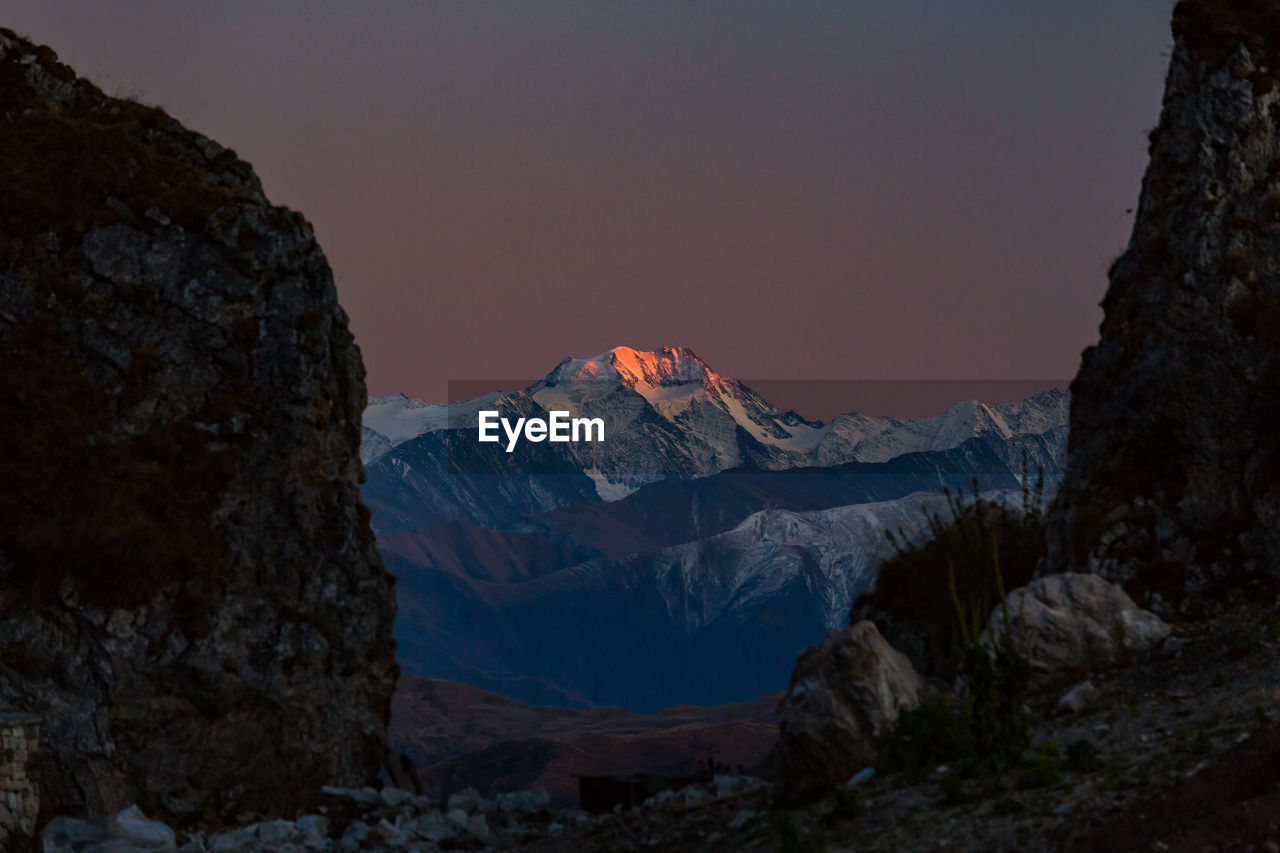 Sunset illuminates the mountain. scenic view of snowcapped mountains against sky