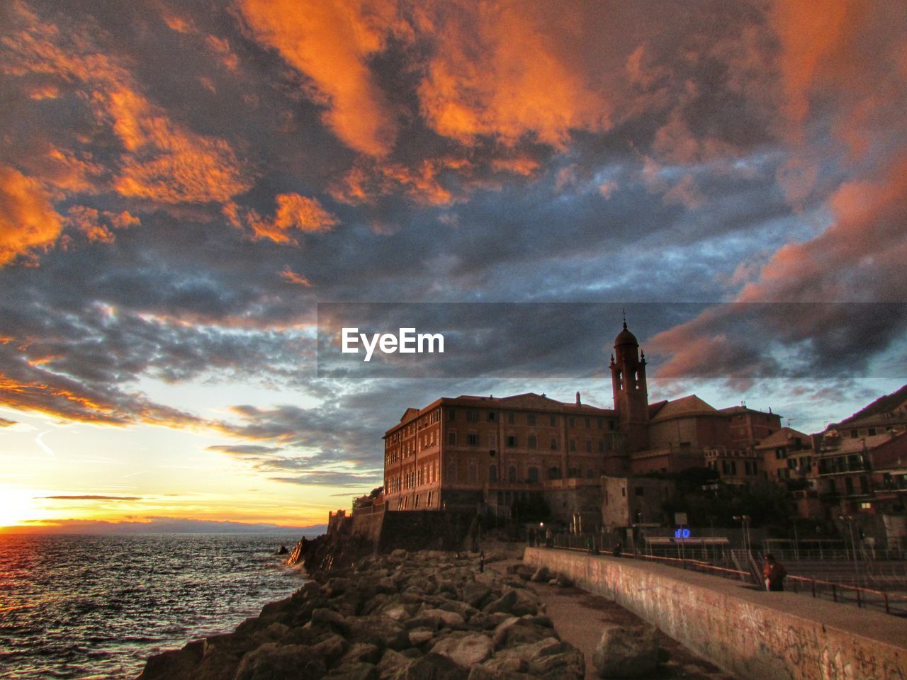 Low angle view of historic building by sea against sky during sunset