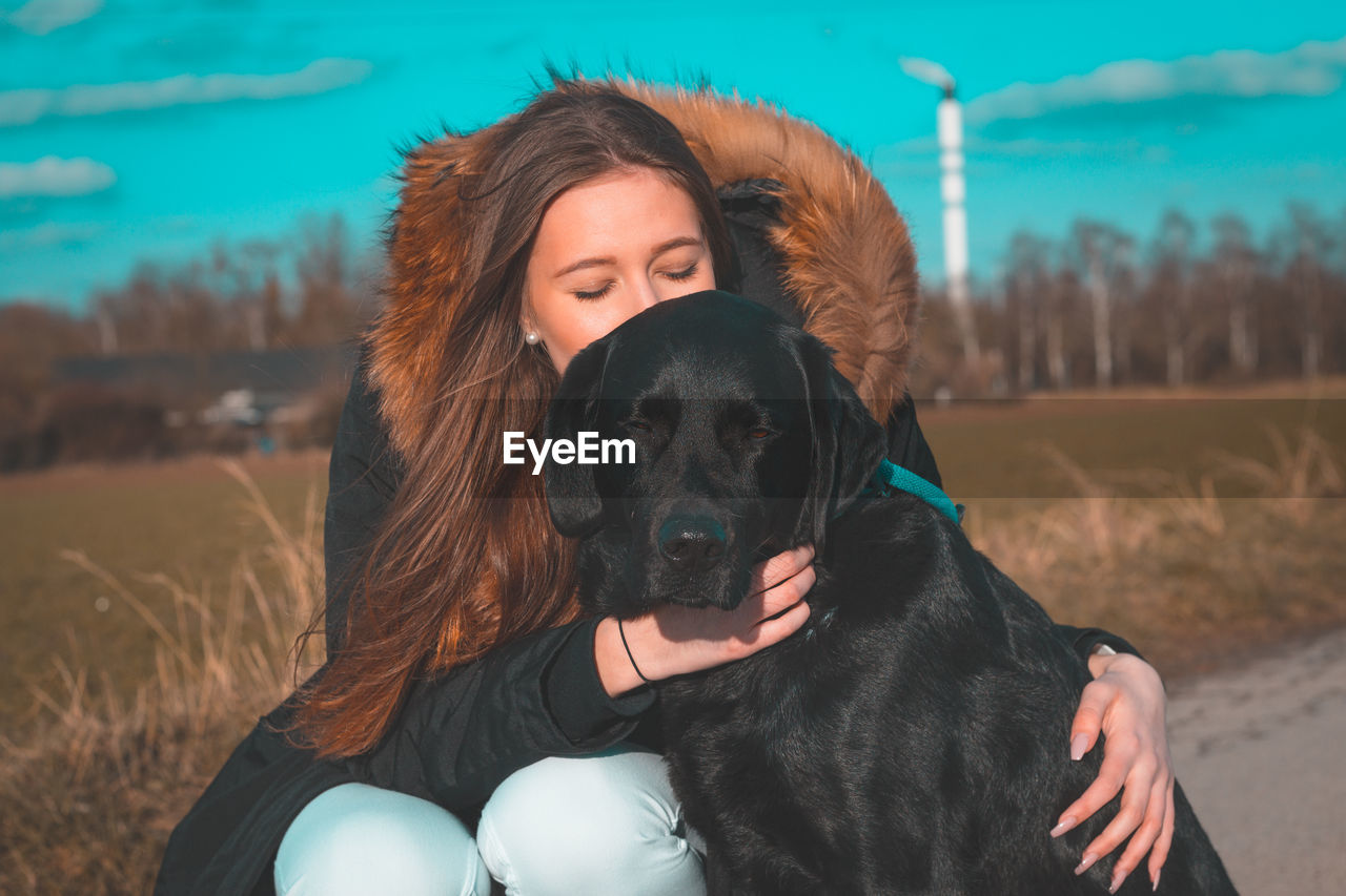 Portrait of woman with dog on roadside during winter