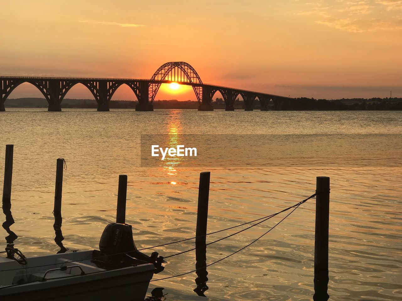 BRIDGE OVER RIVER AGAINST SKY AT SUNSET