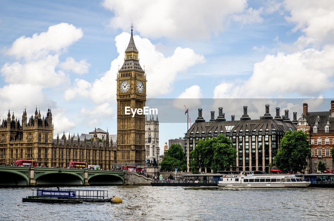 River by big ben against cloudy sky