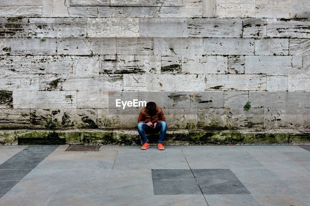 Man sitting against wall