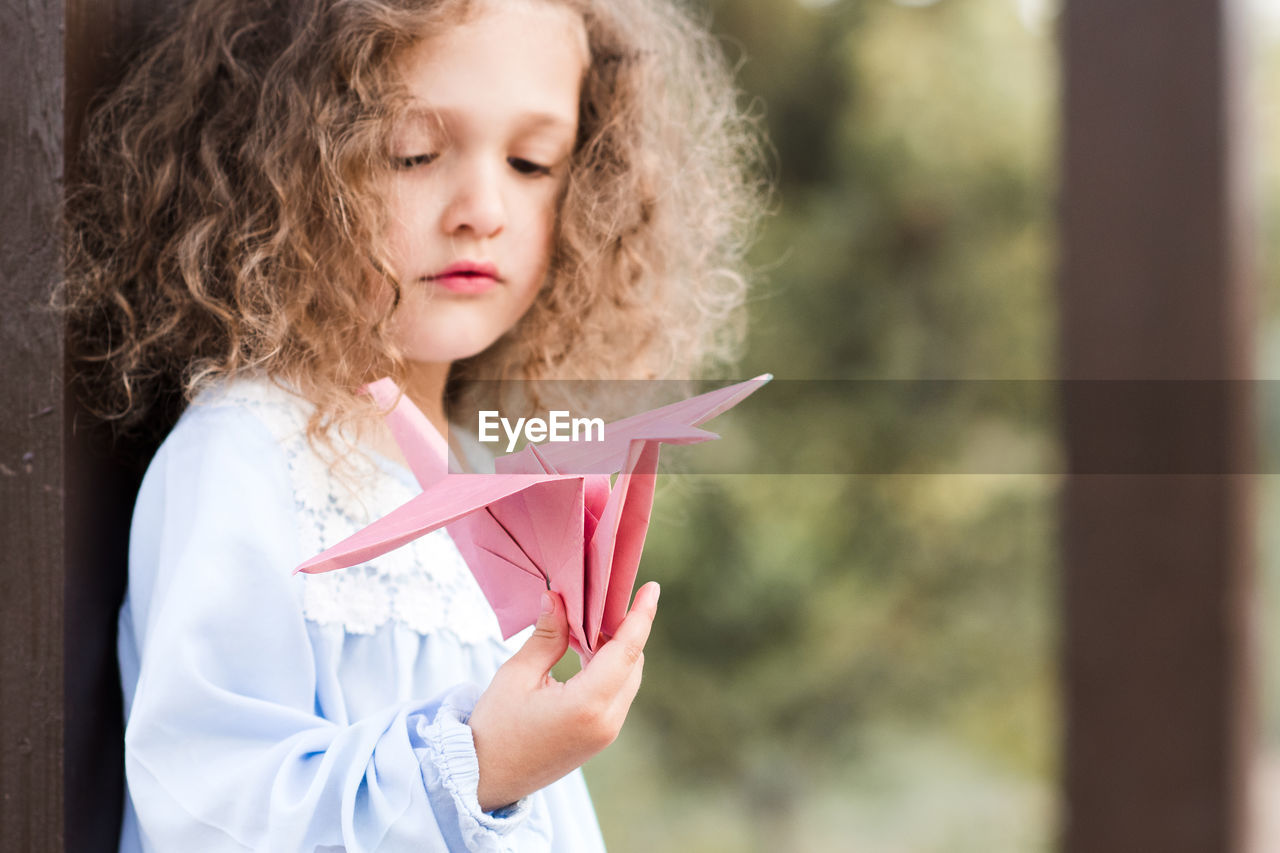 Cute girl looking at origami bird