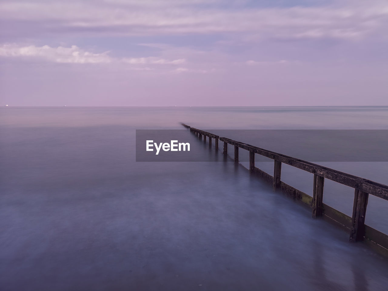 Pier over sea against sky at sunset