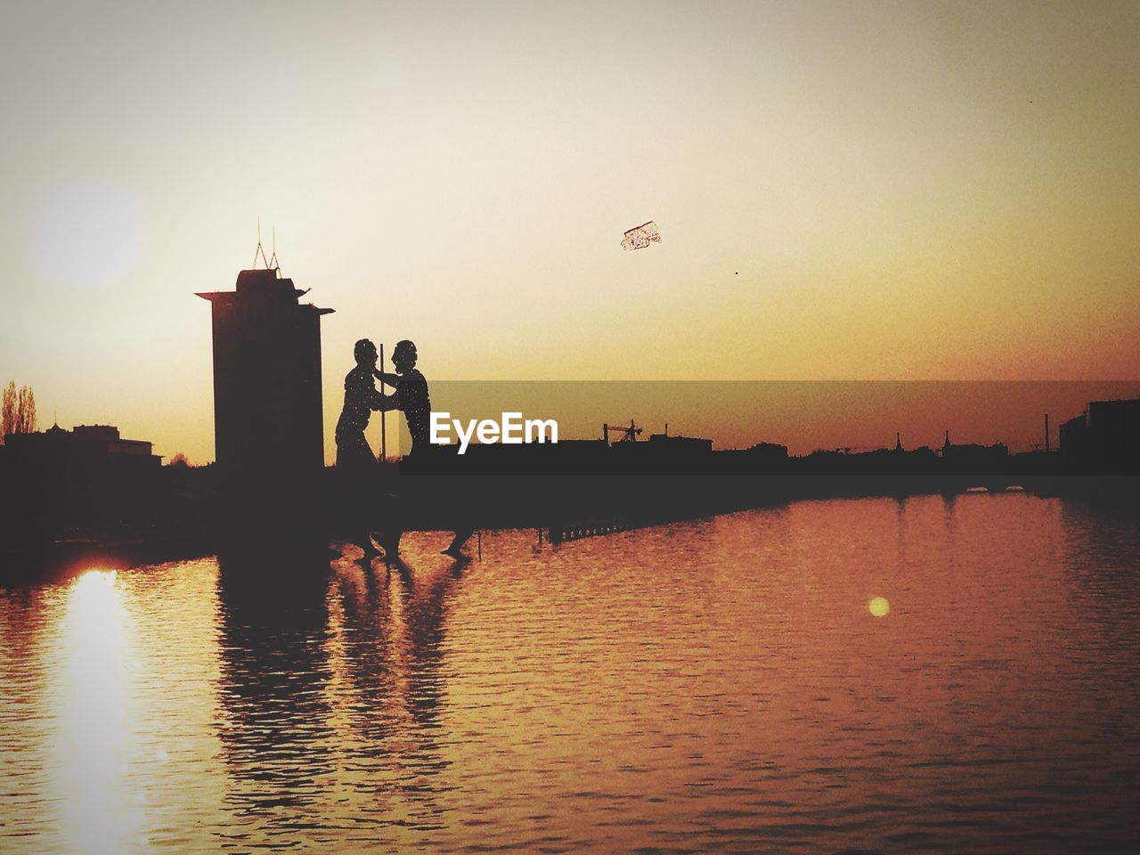 Silhouette of molecule men on river during sunset