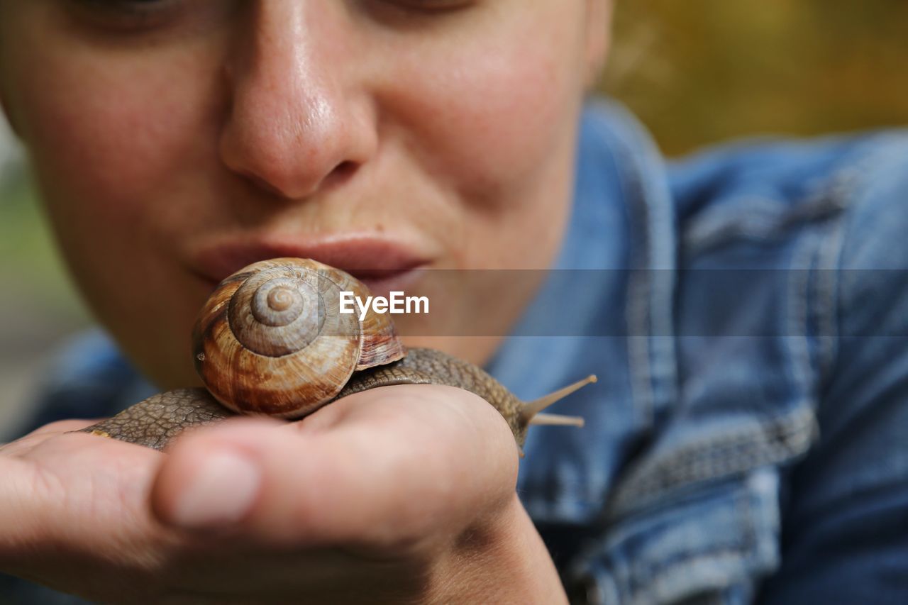 Cropped image of woman kissing snail on palm