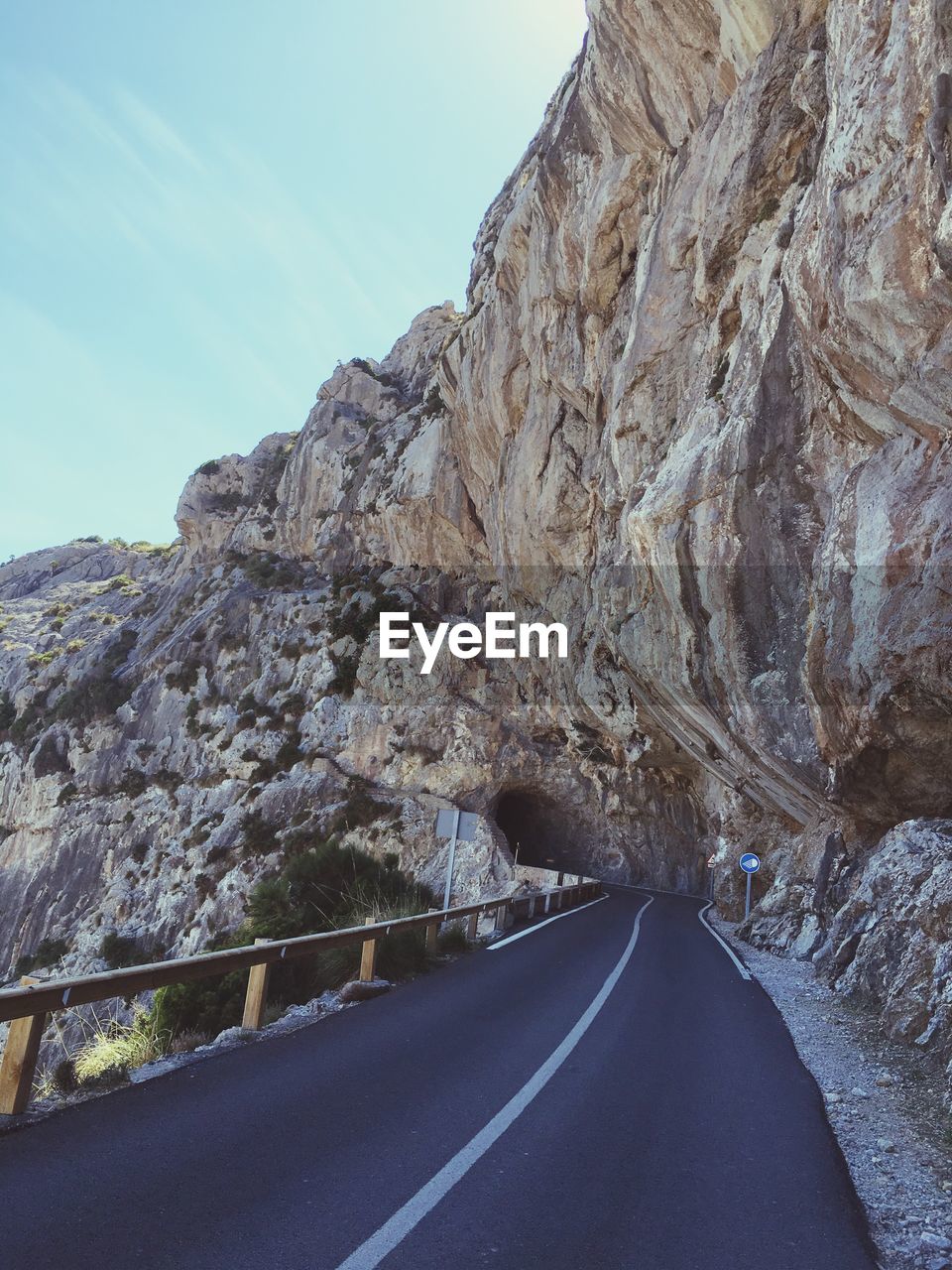 Empty mountain road leading towards cave