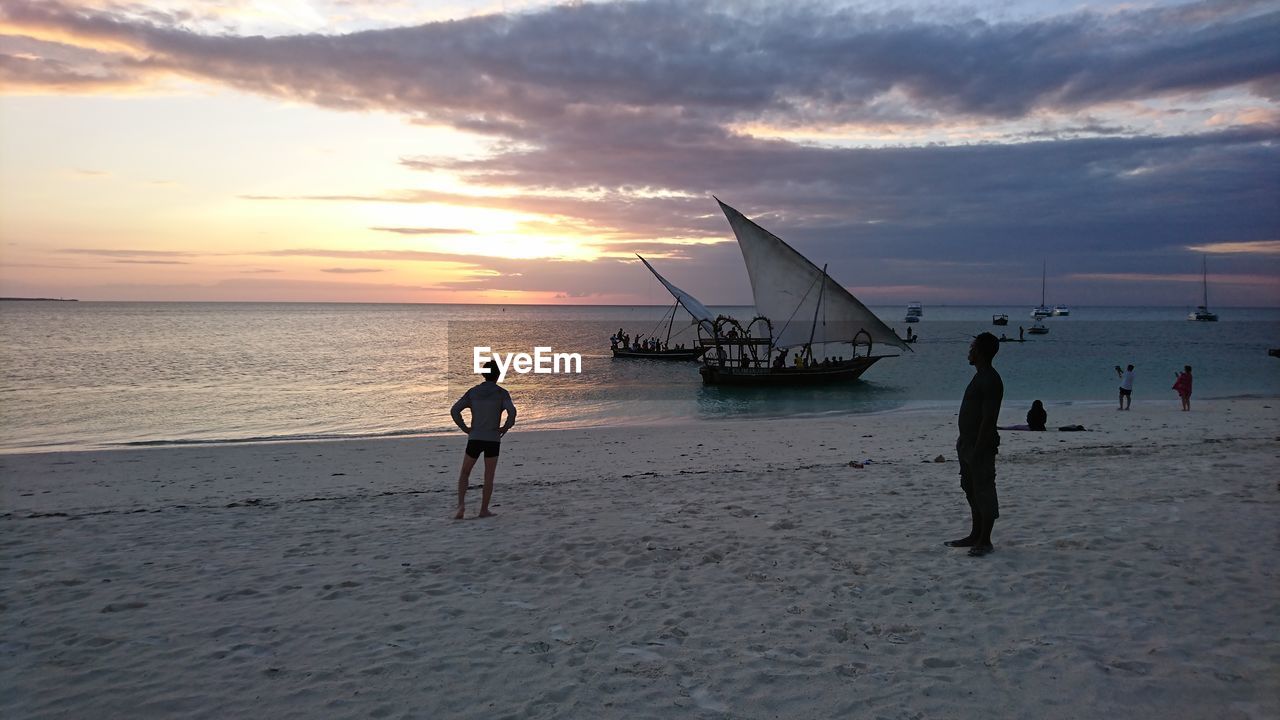 SILHOUETTE PEOPLE PLAYING AT BEACH DURING SUNSET