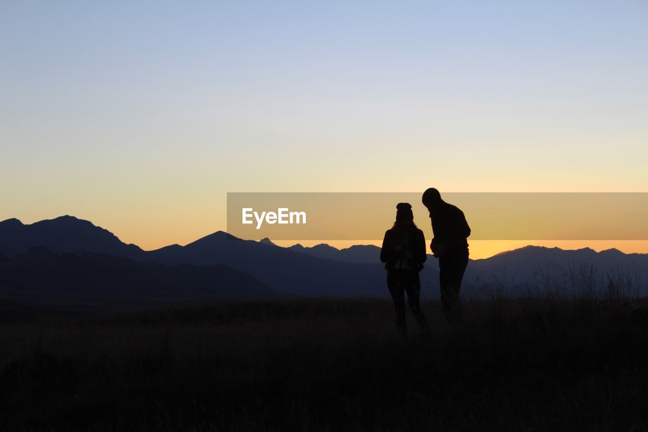 Silhouette people standing on field against clear sky