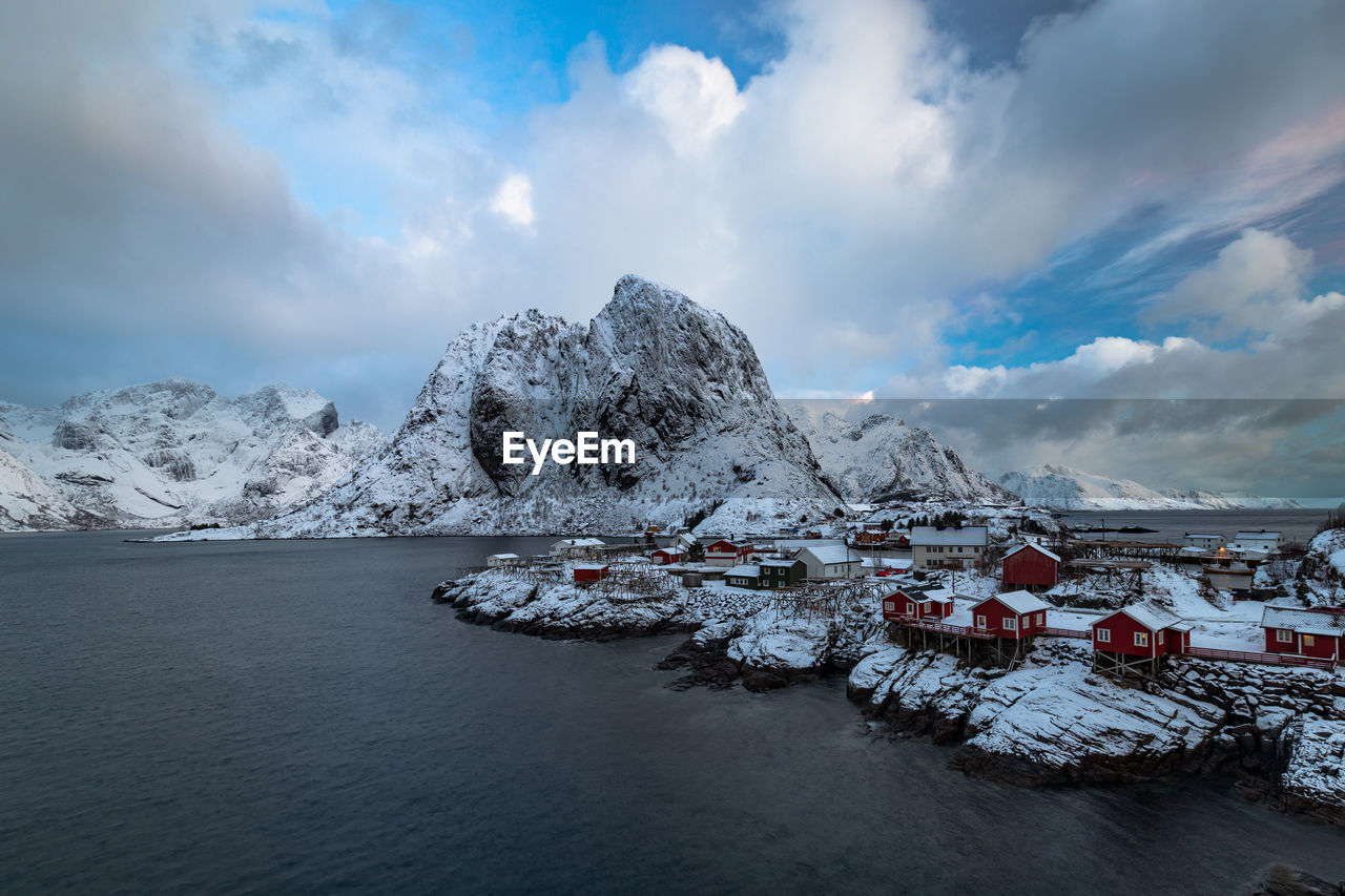 Scenic view of snowcapped mountains by sea against cloudy sky